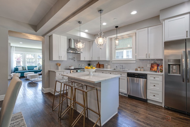 842 Mapleton Ave, Oak Park, IL 60302 - kitchen featuring appliances with stainless steel finishes, wall chimney range hood, dark wood-type flooring, white cabinetry, and a kitchen bar