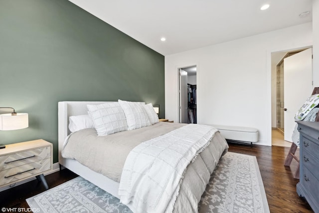bedroom with recessed lighting, dark wood-style floors, a walk in closet, and baseboards