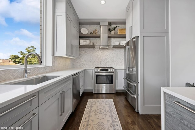 kitchen featuring appliances with stainless steel finishes, a sink, wall chimney exhaust hood, backsplash, and recessed lighting