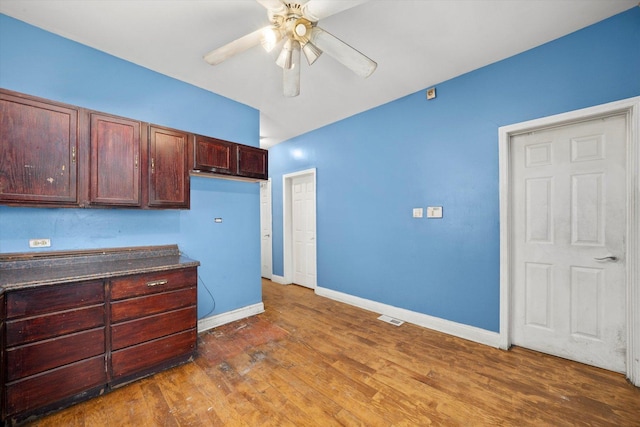 kitchen with a ceiling fan, dark countertops, and wood finished floors