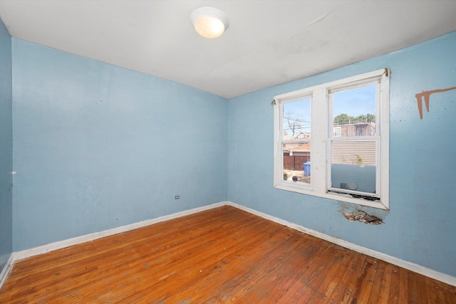 unfurnished room with hardwood / wood-style flooring and baseboards