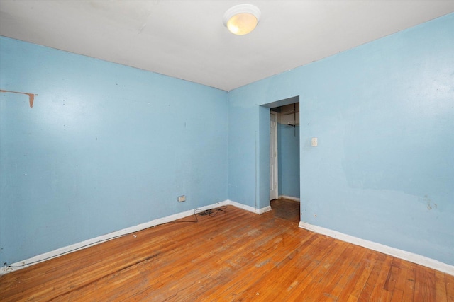 empty room with hardwood / wood-style floors and baseboards