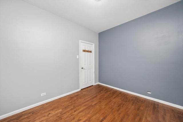 spare room featuring baseboards and wood finished floors