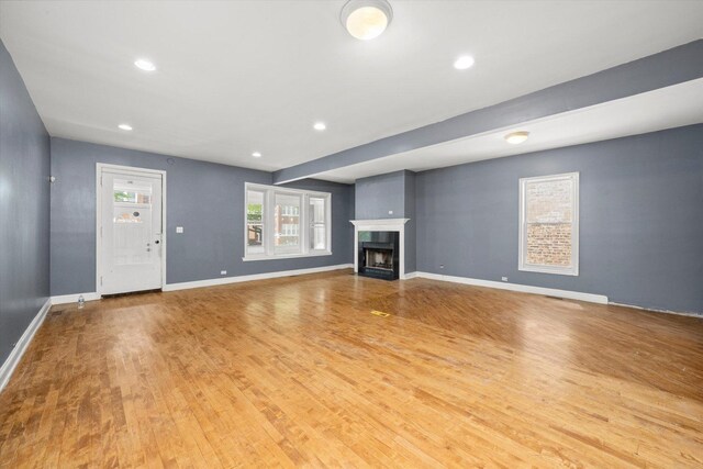 unfurnished living room with wood finished floors, a fireplace, and recessed lighting