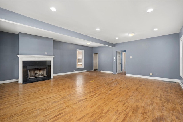 unfurnished living room with light wood-type flooring, a tiled fireplace, and recessed lighting