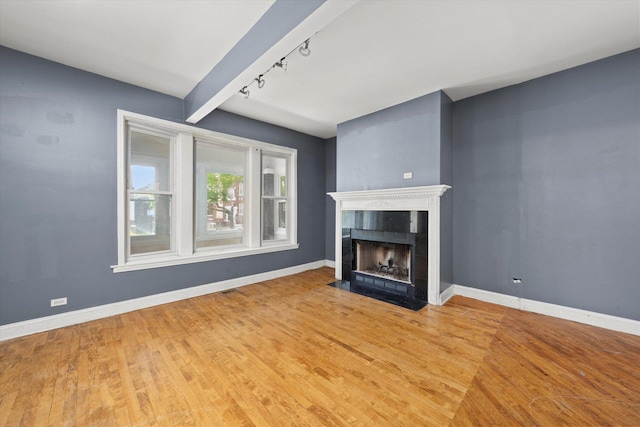 unfurnished living room with rail lighting, wood finished floors, and a tile fireplace