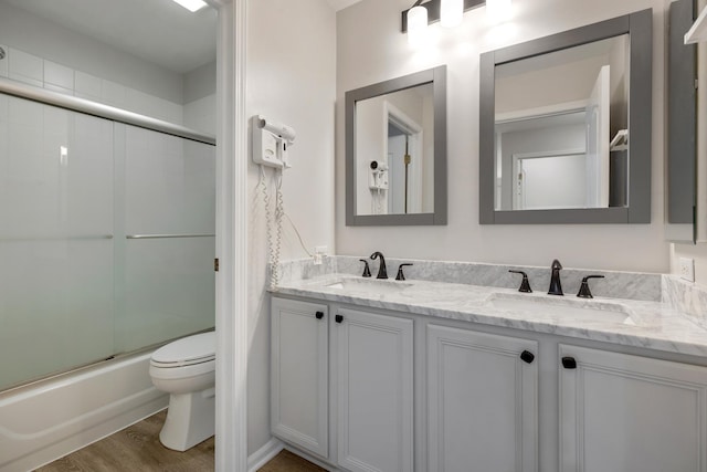 119 Allerton Dr, Schaumburg, IL 60194 - bathroom featuring toilet, double vanity, combined bath / shower with glass door, and wood finished floors