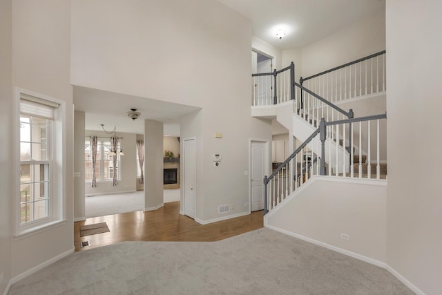 119 Allerton Dr, Schaumburg, IL 60194 - entryway with carpet floors, baseboards, a high ceiling, stairway, and a glass covered fireplace