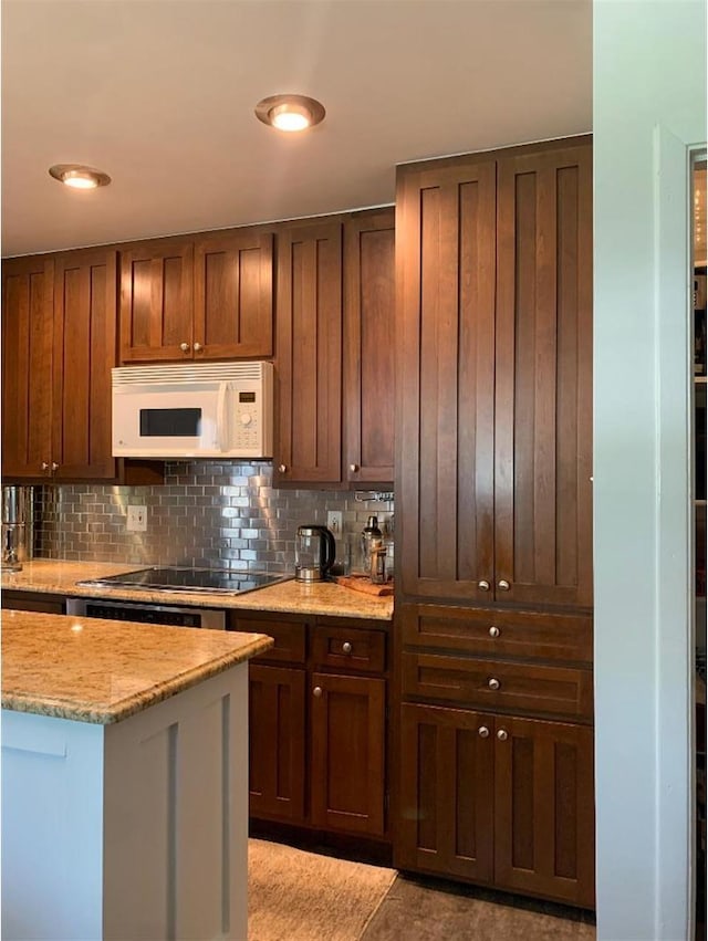 8632 New England Ave, Burbank, IL 60459 - kitchen with white microwave, black electric stovetop, backsplash, and light stone counters