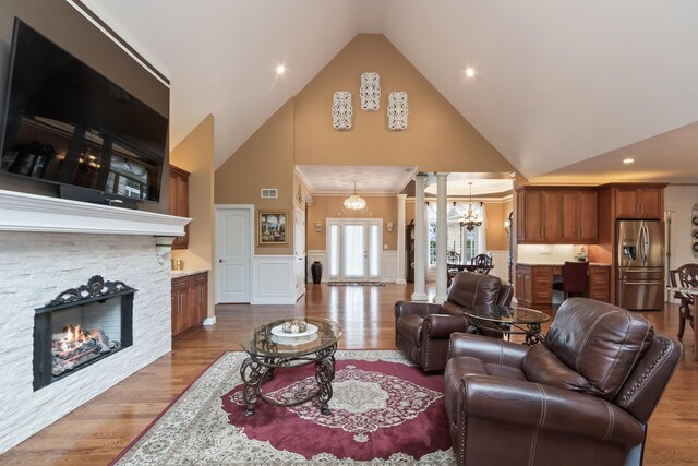 5419 Rita Ave, Crystal Lake, IL 60014 - living room featuring high vaulted ceiling, a chandelier, a stone fireplace, a wainscoted wall, and wood finished floors