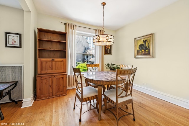dining area with a chandelier, light wood-style flooring, and baseboards