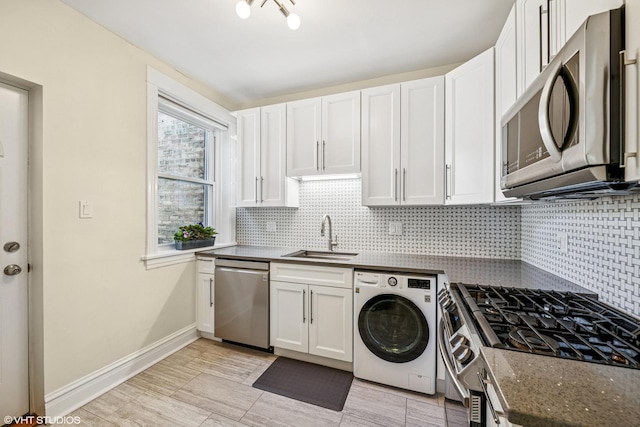 kitchen featuring appliances with stainless steel finishes, washer / clothes dryer, a sink, and tasteful backsplash