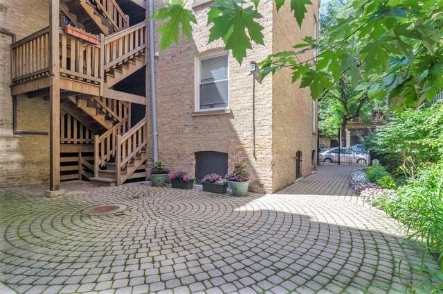 view of side of property featuring brick siding, a patio area, and stairway