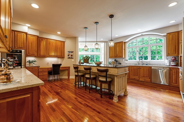 9430 Reserve Dr, Caledonia, IL 61011 - kitchen with appliances with stainless steel finishes, brown cabinets, decorative backsplash, a breakfast bar area, and wood finished floors