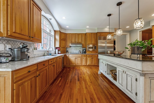 9430 Reserve Dr, Caledonia, IL 61011 - kitchen featuring built in appliances, a sink, dark wood finished floors, light stone countertops, and under cabinet range hood