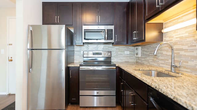 kitchen with stainless steel appliances, a sink, tasteful backsplash, and dark brown cabinets