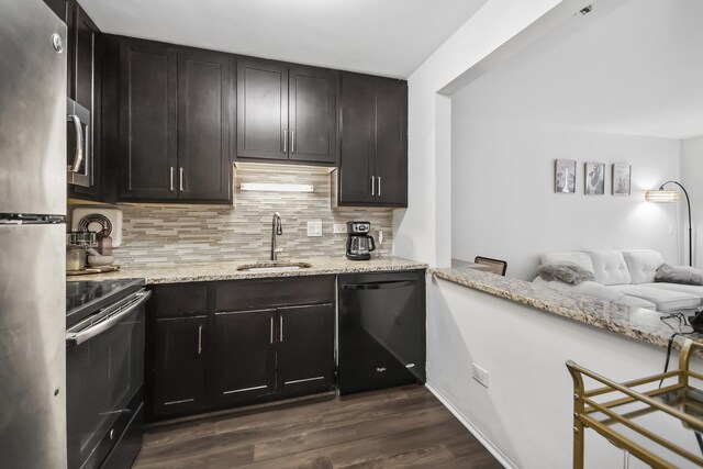 kitchen featuring stainless steel appliances, a sink, backsplash, and light stone countertops