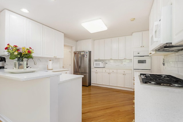 2164 Tellis Ln, Lisle, IL 60532 - kitchen with appliances with stainless steel finishes, tasteful backsplash, white cabinetry, light wood-style floors, and recessed lighting