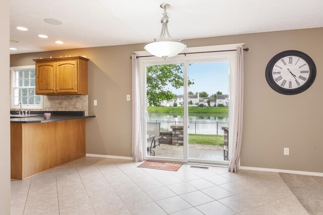 kitchen with dark countertops, a sink, healthy amount of natural light, decorative backsplash, and recessed lighting