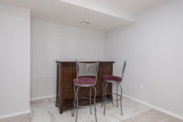 indoor dry bar with light marble finish floors and baseboards