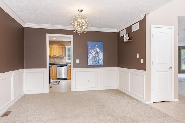 unfurnished dining area featuring a chandelier, light carpet, ornamental molding, wainscoting, and light tile patterned floors