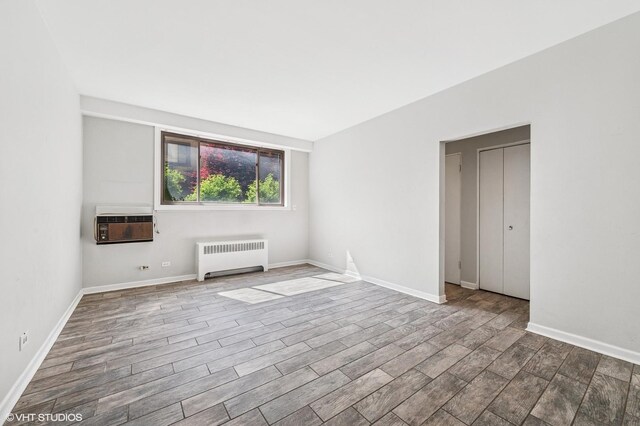 spare room featuring radiator heating unit, baseboards, and an AC wall unit