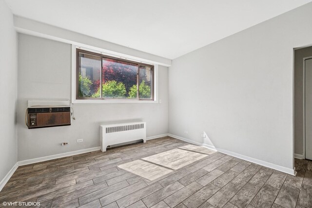 empty room with radiator, wood finished floors, and baseboards
