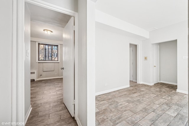 corridor featuring radiator heating unit and baseboards