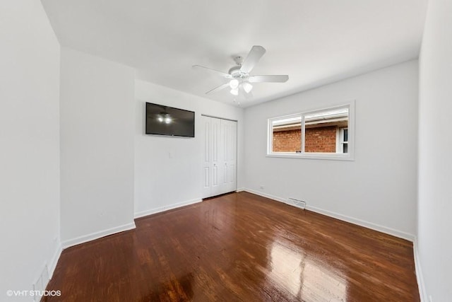 unfurnished bedroom with wood finished floors, a closet, baseboards, and a ceiling fan