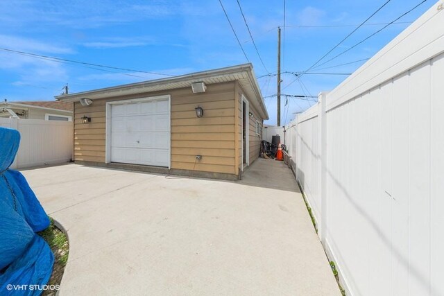 detached garage featuring fence and driveway
