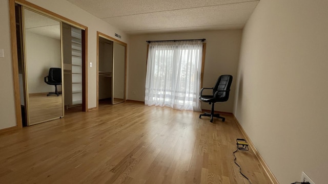 6221 N Niagara Ave Unit 401, Chicago, IL 60631 - unfurnished bedroom featuring two closets, light wood-type flooring, baseboards, and a textured ceiling