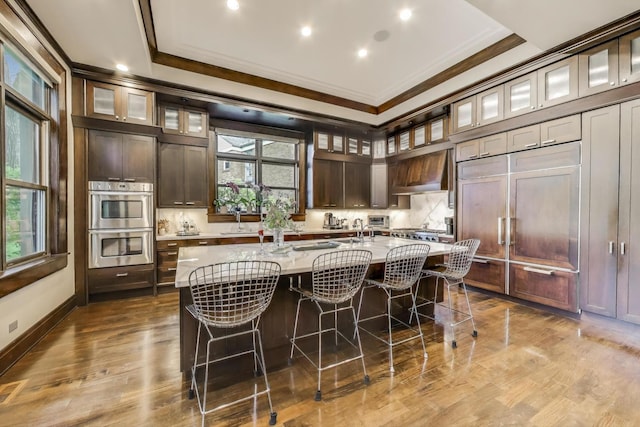 6535 N Tower Circle Dr, Lincolnwood, IL 60712 - kitchen featuring crown molding, double oven, custom range hood, a kitchen bar, and an island with sink
