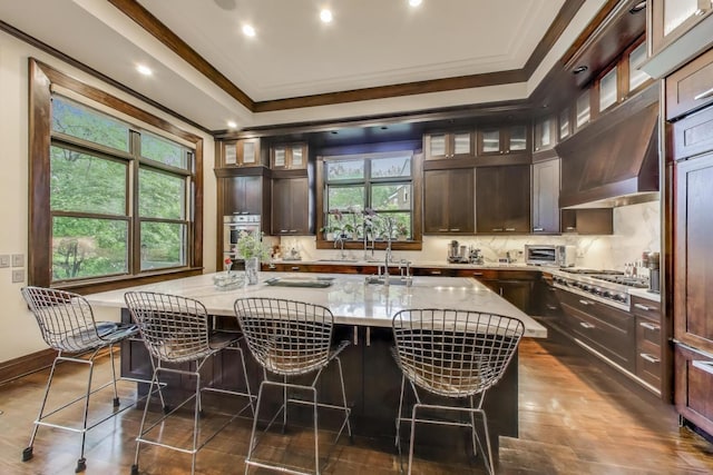 6535 N Tower Circle Dr, Lincolnwood, IL 60712 - kitchen with crown molding, a center island with sink, a breakfast bar area, dark brown cabinetry, and recessed lighting