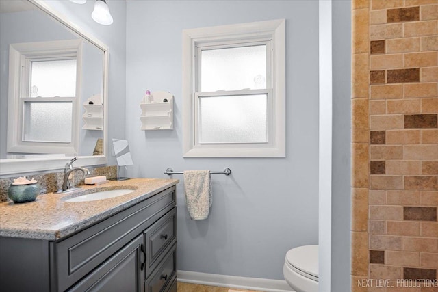 bathroom featuring healthy amount of natural light, vanity, and toilet