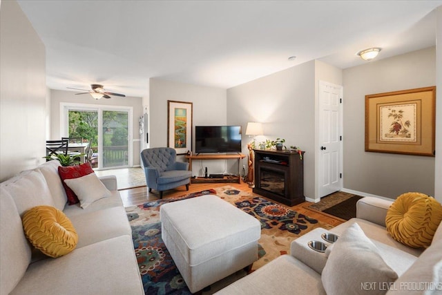 living room with wood finished floors, ceiling fan, and a fireplace