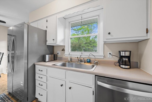 kitchen featuring stainless steel appliances, a sink, light countertops, and white cabinets