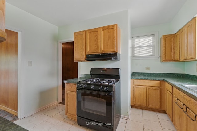 kitchen with black range with gas cooktop, under cabinet range hood, dark countertops, and light tile patterned floors