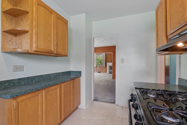 kitchen with open shelves, light colored carpet, dark countertops, black gas range, and baseboards