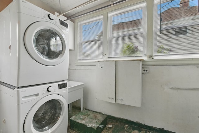laundry area with estacked washer and dryer and healthy amount of natural light
