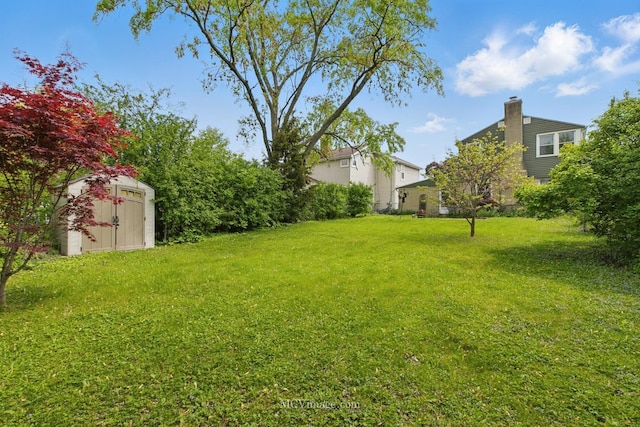 view of green lawn with a storage unit and an outbuilding