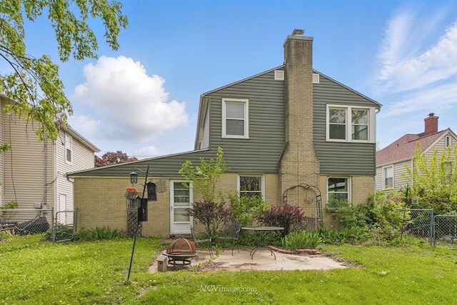back of property with a fire pit, brick siding, a chimney, and a patio area