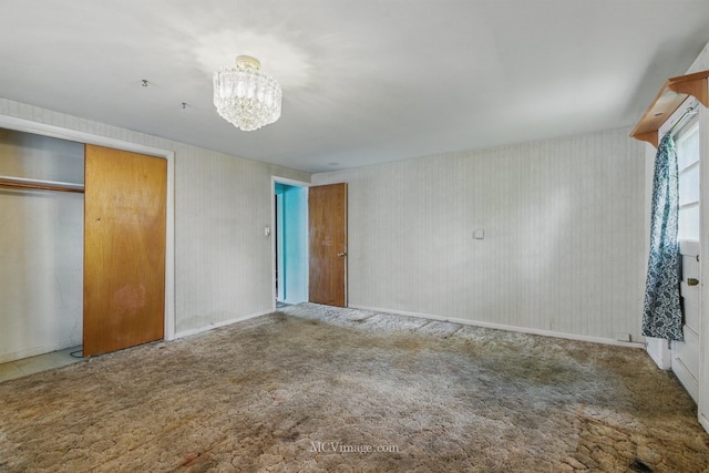 unfurnished bedroom with a chandelier, carpet floors, a closet, and baseboards