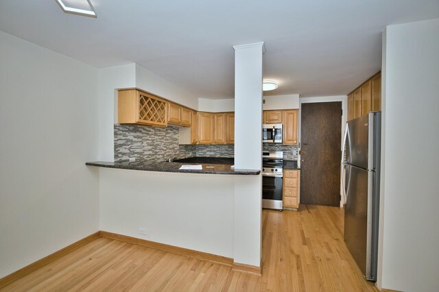 6007 N Sheridan Rd Unit 25F, Chicago, IL 60660 - kitchen featuring appliances with stainless steel finishes, light wood-style floors, backsplash, a peninsula, and baseboards