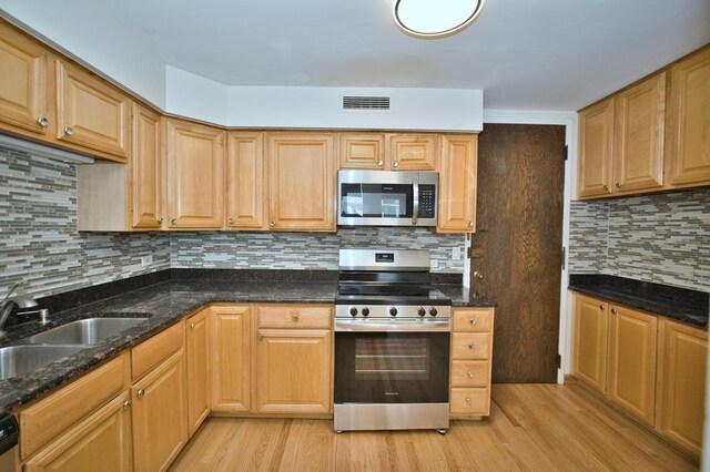 6007 N Sheridan Rd Unit 25F, Chicago, IL 60660 - kitchen with stainless steel appliances, a sink, light wood-type flooring, dark stone counters, and tasteful backsplash