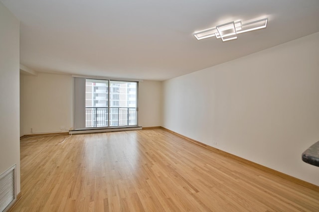 6007 N Sheridan Rd Unit 25F, Chicago, IL 60660 - empty room with light wood-type flooring, a baseboard heating unit, and baseboards