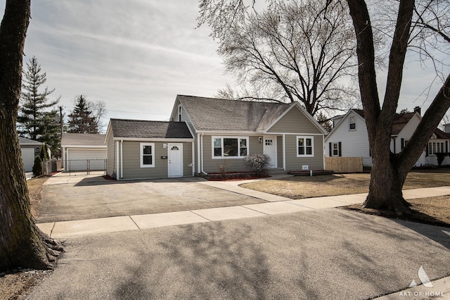 view of front of property featuring fence, an outdoor structure, a shingled roof, and a detached garage