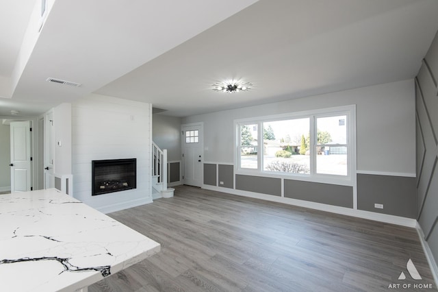 unfurnished living room with light wood-style flooring, a large fireplace, and baseboards