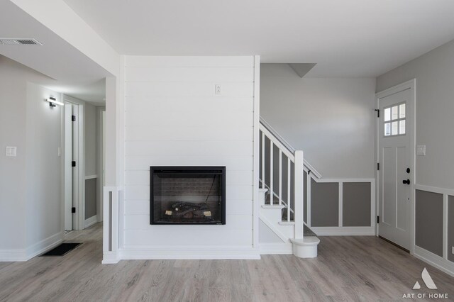 unfurnished living room with wood finished floors, stairway, baseboards, and a fireplace