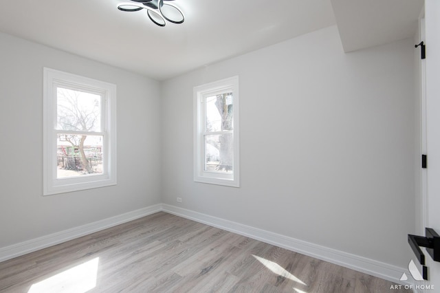 unfurnished room featuring light wood-type flooring, plenty of natural light, and baseboards
