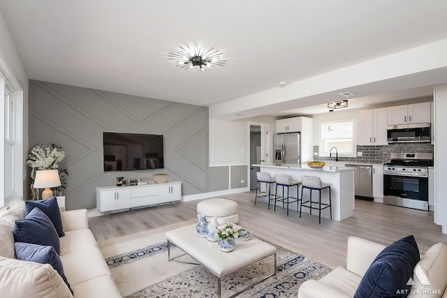 living room featuring a decorative wall and light wood-style floors